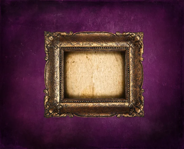 Пустая золотая рамка на фиолетовой гранж-стене — стоковое фото