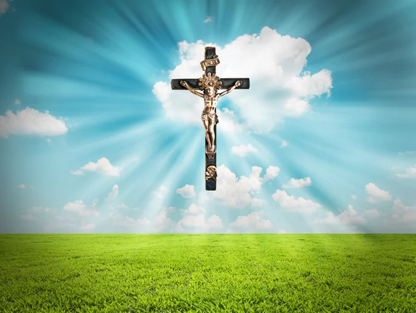 Jesus Christ on cross radiates light in sky over landscape — Stock Photo, Image