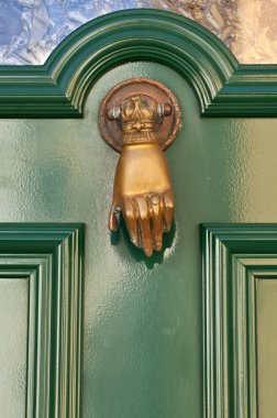Old knocker in the shape of a hand on a door clipart