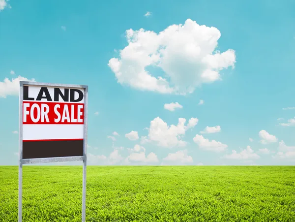 Земля для продажу знак на порожньому зеленому полі — стокове фото
