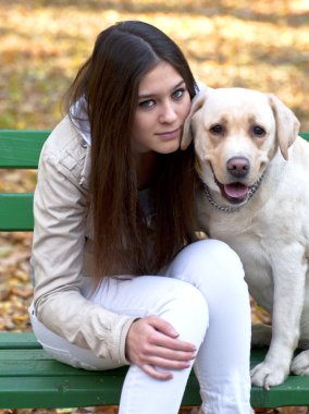 Beautiful girl and her dog sitting on bench in autumn park clipart