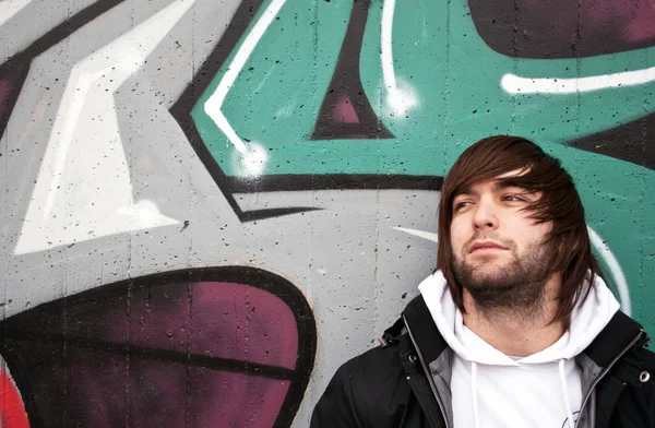 stock image Young man posing in front of a colorful graffiti wall