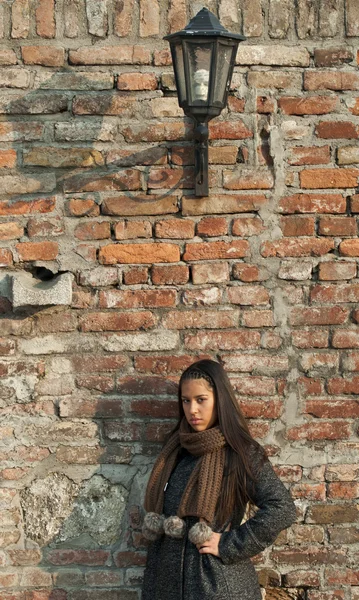 Beautiful woman leaned against brick wall — Stock Photo, Image