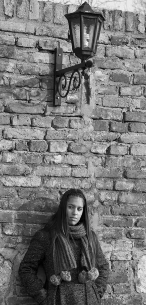 Belle femme appuyée contre un mur de briques en noir et blanc — Photo