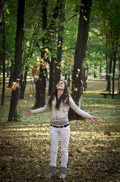 Jovem menina jogando folhas de outono na bela floresta — Fotografia de Stock