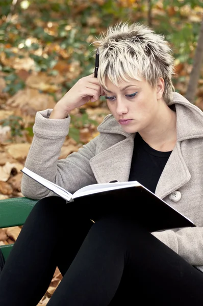Красива студентка читає і розслабляється в парку — стокове фото