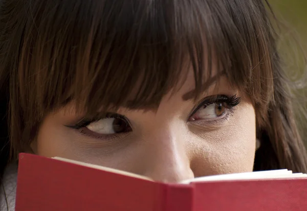 Mooi meisje zichzelf verstopt achter een boek — Stockfoto