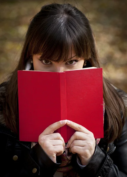 Hermosa chica escondida detrás del libro — Foto de Stock