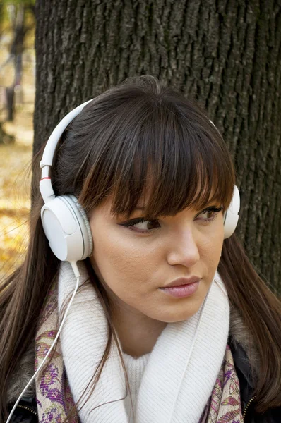 公園で音楽を聞くヘッドフォンを持つ若い魅力的な女性、 — ストック写真