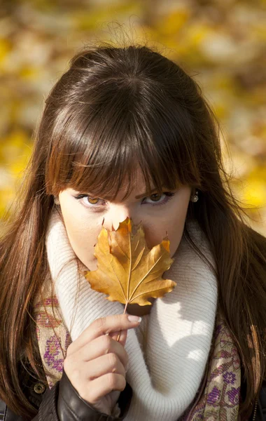 Mysterious portrait of beautiful woman hiding behind autumn leaf — Stock Photo, Image