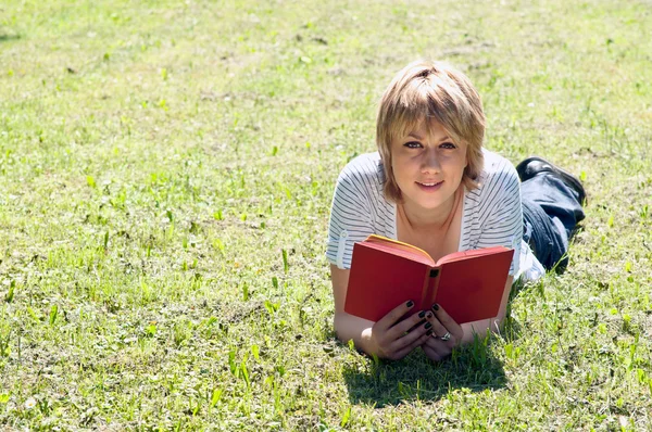 Ragazza sdraiata sull'erba e libro di lettura — Foto Stock