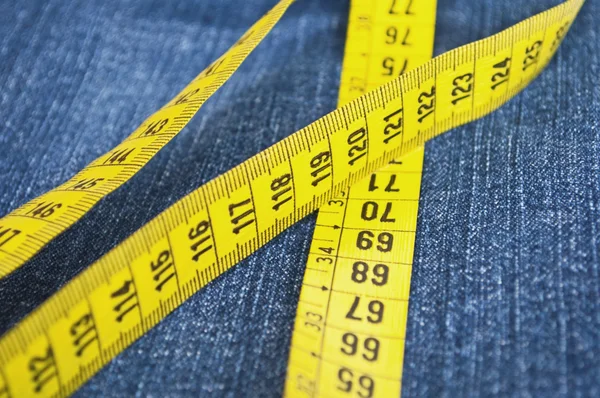 Blue jeans and measure tape - concept of overweight — Stock Photo, Image
