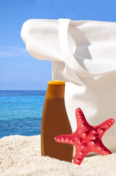 Beach bag, sun cream and starfish on tropical beach - Holiday co — Stock Photo, Image