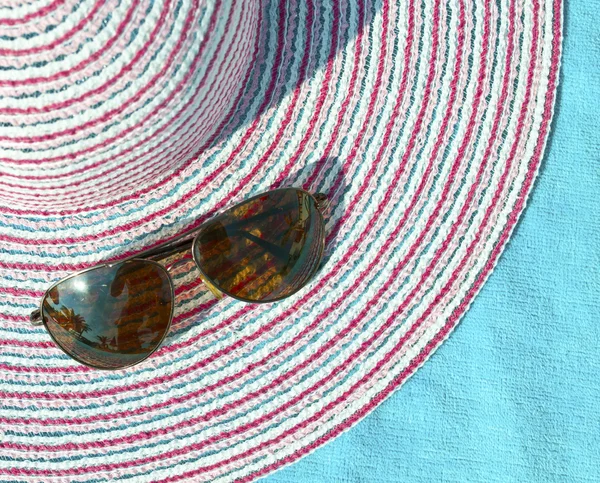 Conceito de verão com chapéu de palha e óculos de sol em toalha azul — Fotografia de Stock