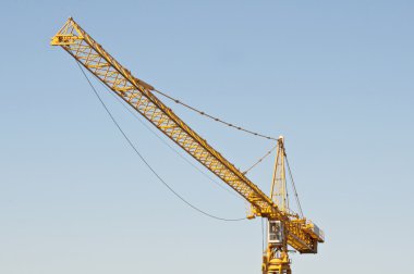 Yellow crane against blue sky clipart