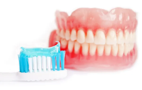 Denture and tooth paste isolated on white — Stock Photo, Image