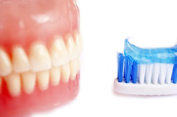 Prótesis dentales y cepillo de dientes con pasta dental aislada en blanco — Foto de Stock