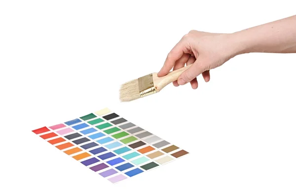 Main avec pinceau et échantillons de peinture colorés — Photo