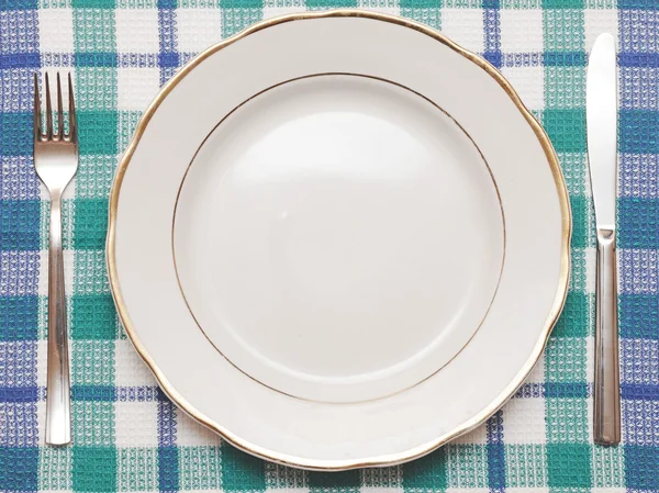 Cuchillo, plato blanco y tenedor sobre mantel a cuadros azul —  Fotos de Stock