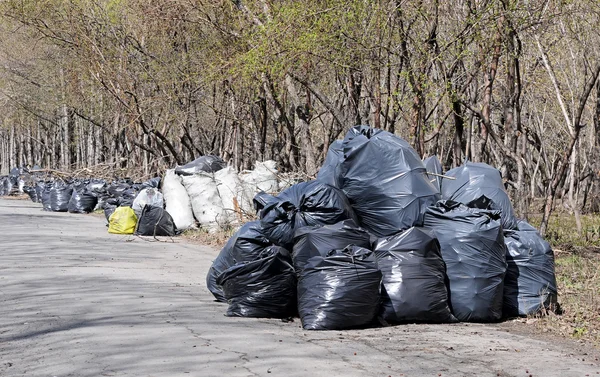 Hromadu černý odpadkové pytle s vysokými městských domů v — Stock fotografie