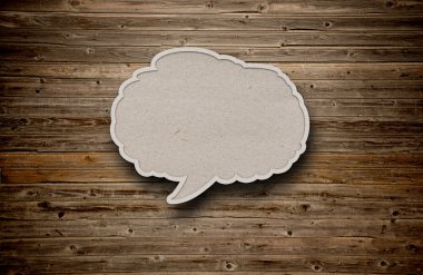 Blank recycled paper speech bubble on wood background clipart