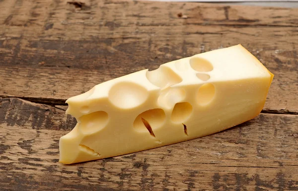 Pedaço de queijo em um fundo de madeira — Fotografia de Stock