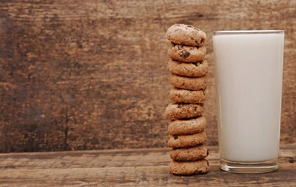 Vidro de leite e biscoitos na mesa de madeira — Fotografia de Stock