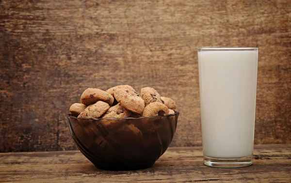 Glass of milk and chocolate chip cookies on wooden table — Stock Photo, Image