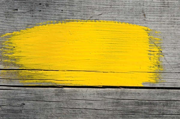 stock image Yellow stroke of the paint brush on wooden background