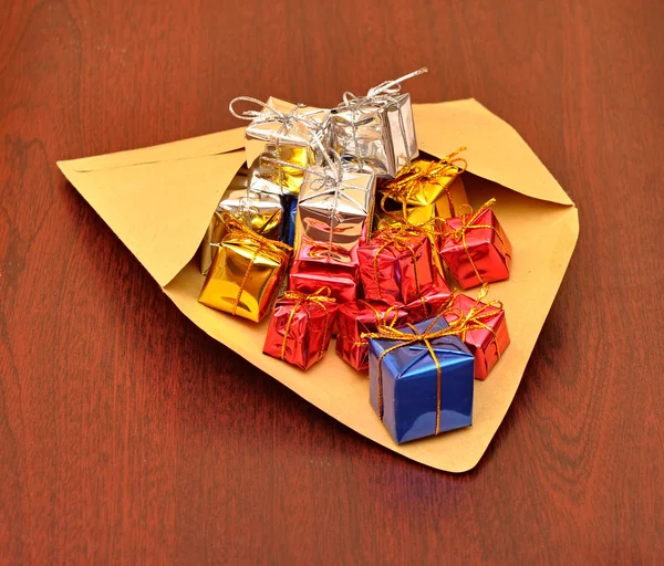 Boîtes-cadeaux colorées avec enveloppe sur fond de bois — Photo