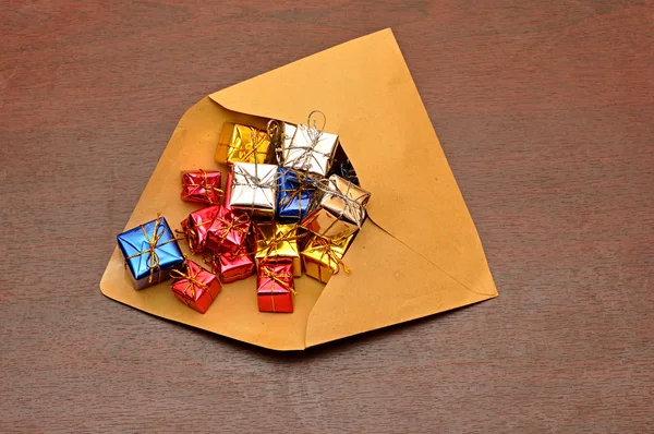 Zarfın üzerinde tahta arka plan ile renkli hediye kutuları — Stok fotoğraf
