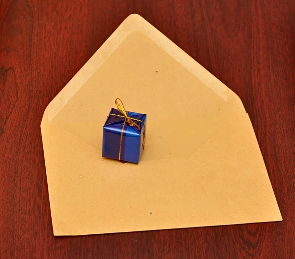 Подарункова коробка з конвертом на фоні дерева — стокове фото