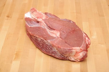 Huge red meat chunk on wooden table clipart