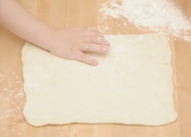 Child's hands kneading dough on wooden table clipart