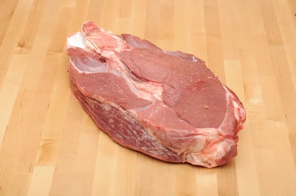 Pedaço de carne vermelha enorme na mesa de madeira — Fotografia de Stock