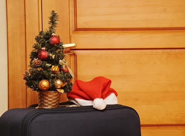 Resväska och santa hat mot en trädörr. — Stockfoto