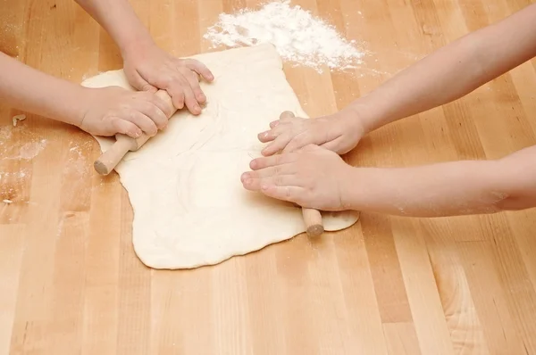 Child's hands kneading dough on wooden table — Stock Photo, Image