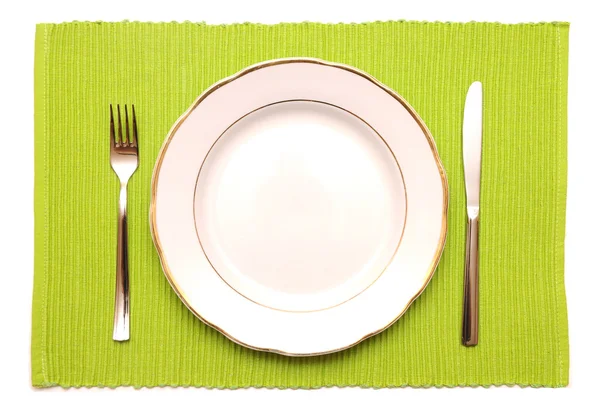 Knife, fork and white plate on a green napkin — Stock Photo, Image