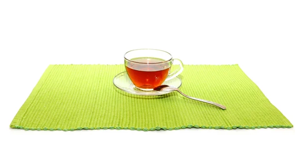 Šálek čaje s lžící na zelený ubrousek — Stock fotografie