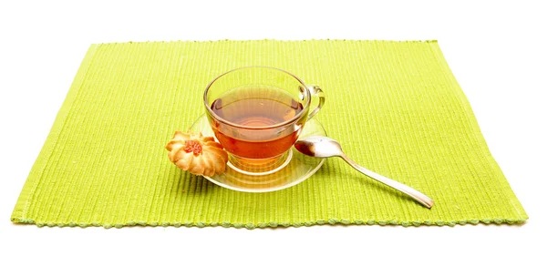 Šálek čaje s lžící na zelený ubrousek — Stock fotografie