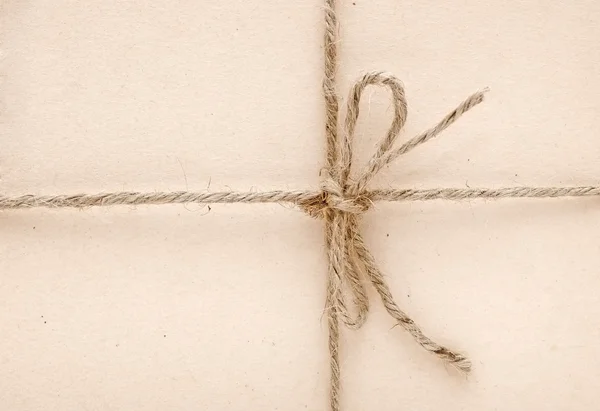 String tied in a bow on a brown paper — Stock Photo, Image
