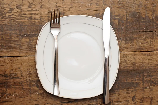 Prázdné misky nůž a vidličku na dřevěný stůl — Stock fotografie