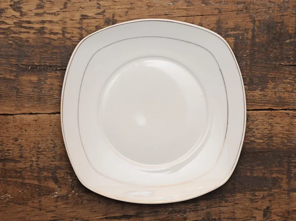 Пустая тарелка на деревянном фоне — стоковое фото