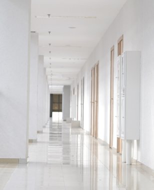 bir tarafta ahşap kapı ile modern beyaz uzun koridor
