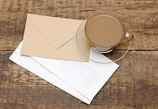 Puste koperty i filiżance kawy szkła na drewniane biurko — Zdjęcie stockowe