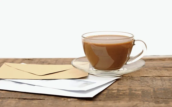 Envelopes em branco e uma xícara de café de vidro em uma mesa de madeira — Fotografia de Stock