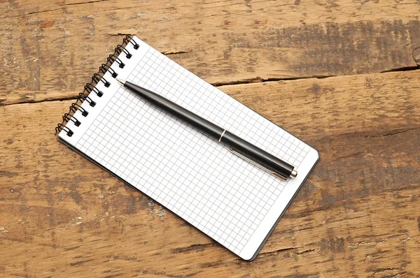 Ahşap masa üstünde kalem ile boş bir not defteri — Stok fotoğraf