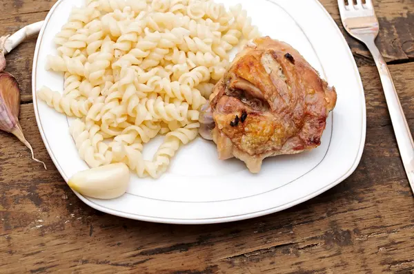 Un plato de pasta y pollo con ajo sobre fondo de madera — Foto de Stock