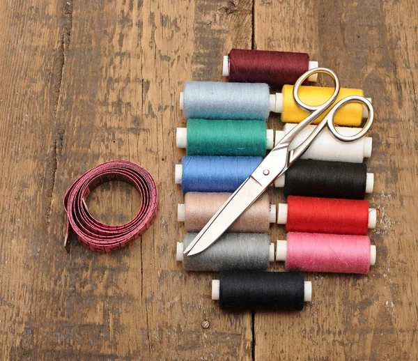 Colorful threads and old scissors on the old wooden table — Stock Photo, Image
