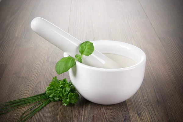 Mortar with fresh herbs on wood background — Stock Photo, Image